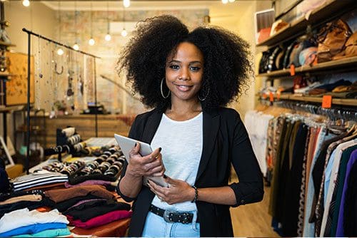 Portrait of the owner of a clothing store at the entrance of the new business with the tablet in hand to analyze the sales
